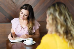 Deux femmes dans un café, l’une écrivant dans un carnet