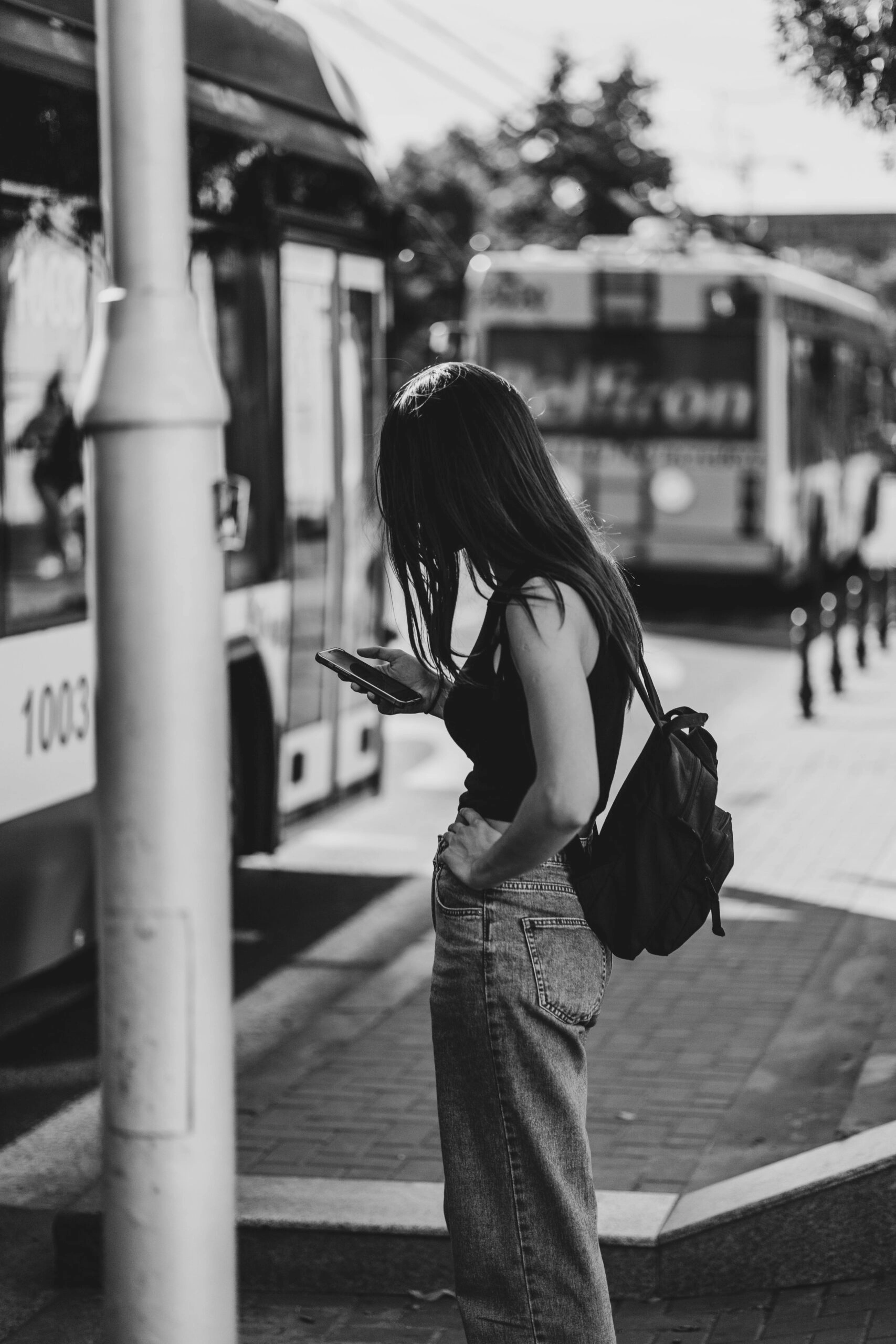 Jeune femme regardant son téléphone à un arrêt de bus